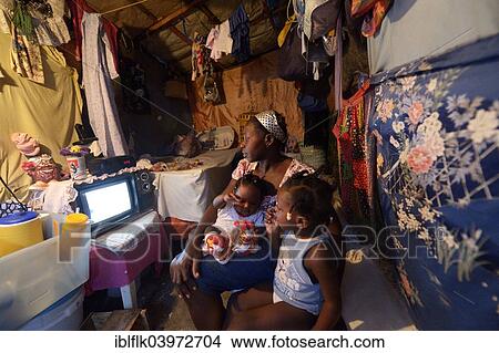 Picture - "Woman with two children watching television in a shack, Camp Icare for earthquake refugees, Fort National, Port-au-Prince, Haiti, North America". Fotosearch