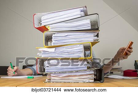 Woman working at a desk behind a stack of files View Large Photo Image Picture - Woman working at a desk behind a stack of files. Fotosearch