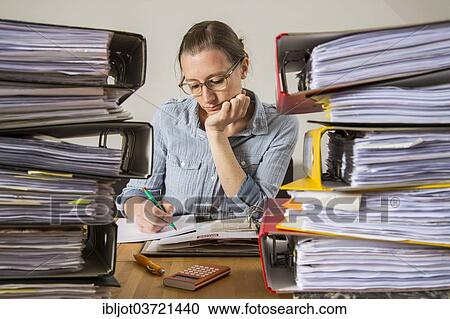 Woman working at a desk between stacks of files View Large Photo Image Stock Image - Woman working at a desk between stacks of files. Fotosearch