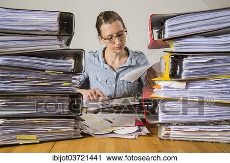 Woman working at a desk between stacks of files View Large Photo Image Stock Image - Woman working at a desk between stacks of files. Fotosearch