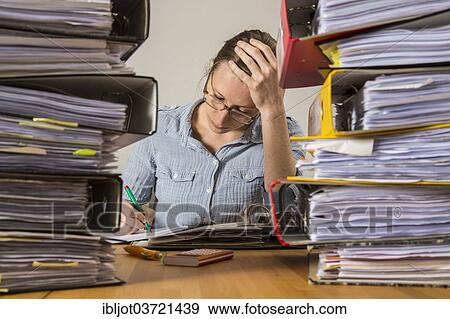 Woman working at a desk between stacks of files View Large Photo Image Stock Photo - Woman working at a desk between stacks of files. Fotosearch