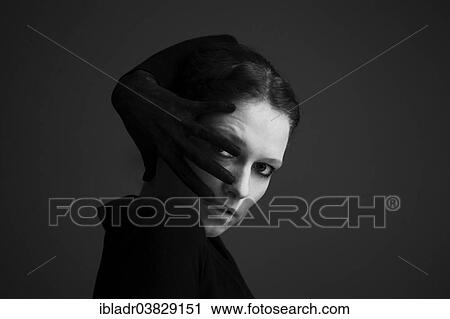 Stock Image - Woman wrapping her hand with a black glove around her head. Fotosearch