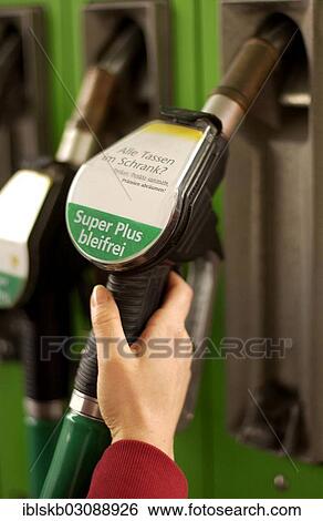 Stock Photograph - "Woman's hand holding a fuel pump nozzle with Super Plus bleifrei, German for Super Plus Unleaded". Fotosearch