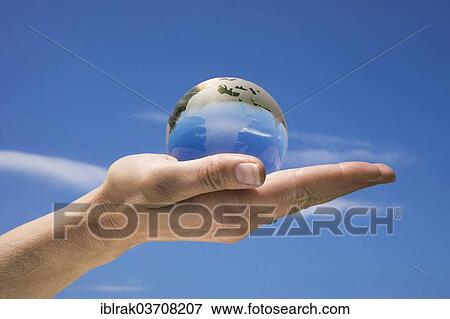 "Woman's hand holding a glass globe against a blue sky, Germany, Europe" View Large Photo Image Stock Photo - "Woman's hand holding a glass globe against a blue sky, Germany, Europe". Fotosearch