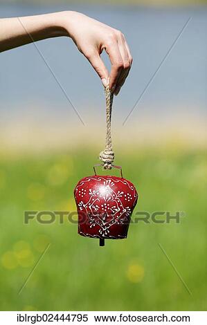 Stock Photography - Woman's hand holding an Allgaeu cowbell. Fotosearch