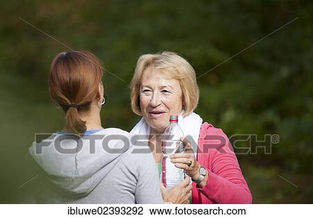 Stock Image - Women taking a break while doing sports outdoors. Fotosearch