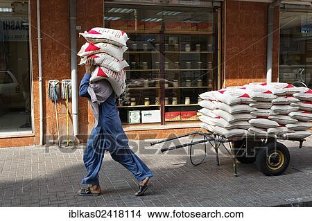 Worker carrying sacks of lentils on his shoulder, Deira, Old Souk, Dubai, United Arab Emirates, Middle East, Asia View Large Photo Image Picture - Worker carrying sacks of lentils on his shoulder, Deira, Old Souk, Dubai, United Arab Emirates, Middle East, Asia. Fotosearch