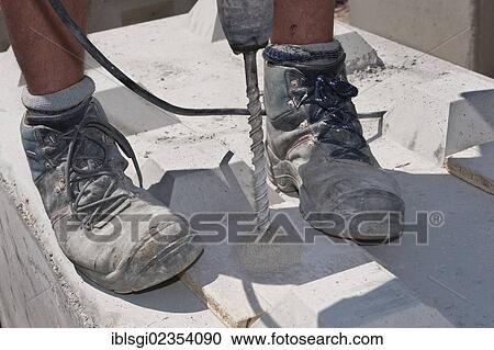 "Worker drilling holes into stone blocks that are to be used at a building site load test at a construction site in Fridolfing, Bavaria, Germany, Europe" View Large Photo Image Stock Image - "Worker drilling holes into stone blocks that are to be used at a building site load test at a construction site in Fridolfing, Bavaria, Germany, Europe". Fotosearch