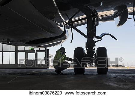 "Worker kneeling next to at the undercarriage of an aircraft, Airport Berlin Brandenburg International, BBI, Berlin, Germany, Europe" View Large Photo Image Stock Photo - "Worker kneeling next to at the undercarriage of an aircraft, Airport Berlin Brandenburg International, BBI, Berlin, Germany, Europe". Fotosearch