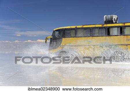 "Yellow bus driving across the Salar de Uyuni, splashing water, Bolivia, South America" View Large Photo Image Stock Image - "Yellow bus driving across the Salar de Uyuni, splashing water, Bolivia, South America". Fotosearch