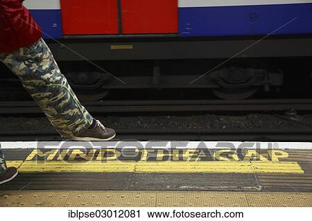 "Yellow marking MIND THE GAP on the floor of a station of the London Underground, a person wearing military pants taking a step towards the rails, London, London region, England, United Kingdom, Europe" View Large Photo Image Stock Image - "Yellow marking MIND THE GAP on the floor of a station of the London Underground, a person wearing military pants taking a step towards the rails, London, London region, England, United Kingdom, Europe". Fotosearch