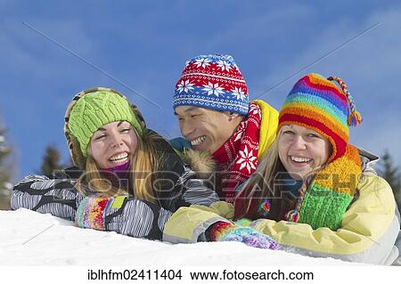 "Young Asian man and two young European women smiling while lying on a mound of snow and wearing colourful winter clothing, Villach, Carinthia, Austria, Europe" View Large Photo Image Picture - "Young Asian man and two young European women smiling while lying on a mound of snow and wearing colourful winter clothing, Villach, Carinthia, Austria, Europe". Fotosearch