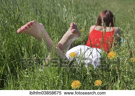 "Young barefoot woman lying on her stomach in a flowering spring meadow, Germany, Europe" View Large Photo Image Stock Photography - "Young barefoot woman lying on her stomach in a flowering spring meadow, Germany, Europe". Fotosearch