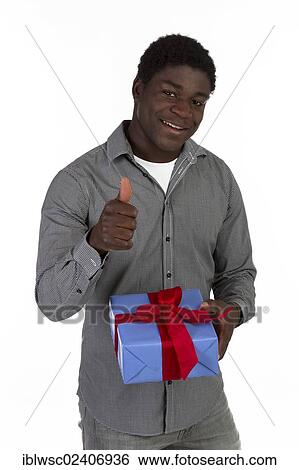Stock Photograph - "Young black man holding a present, thumbs up". Fotosearch