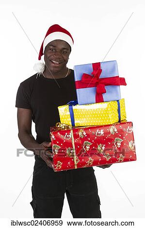 Young black man wearing a Santa hat and holding presents View Large Photo Image Stock Photo - Young black man wearing a Santa hat and holding presents. Fotosearch