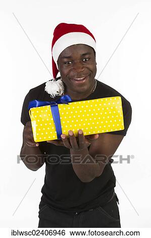 Stock Photograph - Young black man wearing a Santa hat and holding a present. Fotosearch