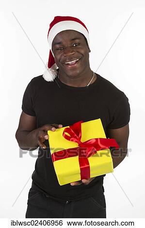 Stock Photograph - Young black man wearing a Santa hat and holding a present. Fotosearch