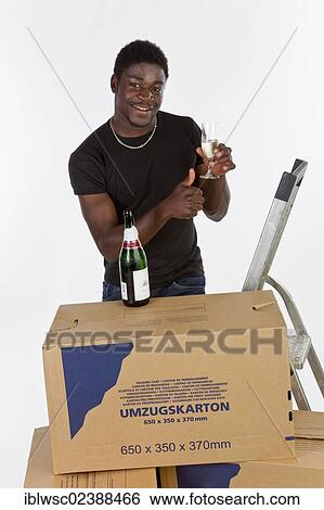 Young black man with moving boxes and a bottle of champagne View Large Photo Image Stock Photograph - Young black man with moving boxes and a bottle of champagne. Fotosearch