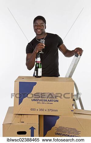 Young black man with moving boxes and a bottle of champagne View Large Photo Image Stock Photography - Young black man with moving boxes and a bottle of champagne. Fotosearch