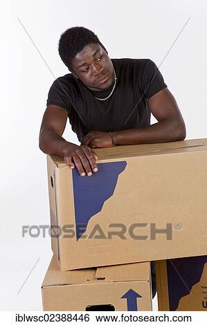 Stock Photograph - Young black man with moving boxes. Fotosearch