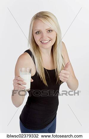 Stock Image - Young blonde woman holding a glass of milk. Fotosearch