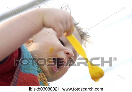 Stock Image - Young boy eating baby food. Fotosearch
