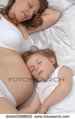 "Young boy lying beside the belly of his pregnant mother, both sleeping" View Large Photo Image Stock Photography - "Young boy lying beside the belly of his pregnant mother, both sleeping". Fotosearch