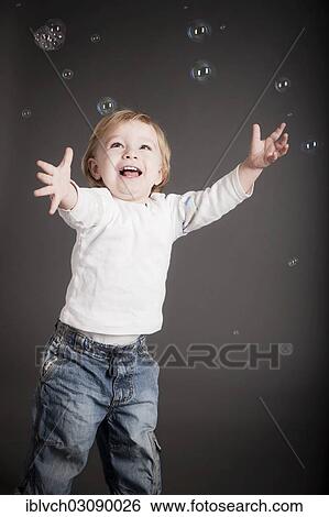 Stock Photograph - "Young boy playing with soap bubbles, Austria, Europe". Fotosearch