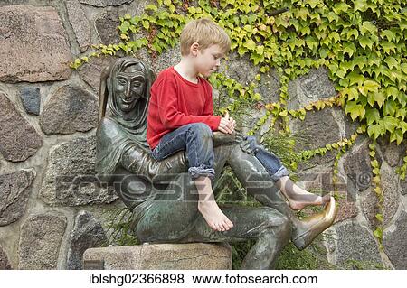 Stock Photo - "Young boy sitting on the Eulenspiegel statue, Moelln, Schleswig-Holstein, Germany, Europe". Fotosearch