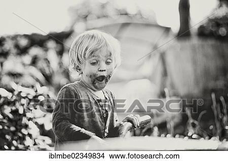 Young boy with his mouth smeared with chocolate looking shocked at a wheelbarrow View Large Photo Image Picture - Young boy with his mouth smeared with chocolate looking shocked at a wheelbarrow. Fotosearch