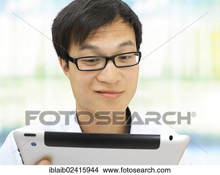 Young businessman, Asian, with glasses, iPad, smiling, friendly, mischievous, optimistic View Large Photo Image Picture - Young businessman, Asian, with glasses, iPad, smiling, friendly, mischievous, optimistic. Fotosearch