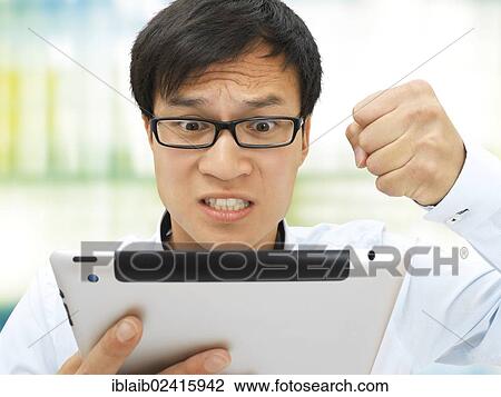 Young businessman, Asian, with glasses, iPad, hand clenched in a fist, upset, angry, stressed out View Large Photo Image Stock Image - Young businessman, Asian, with glasses, iPad, hand clenched in a fist, upset, angry, stressed out. Fotosearch