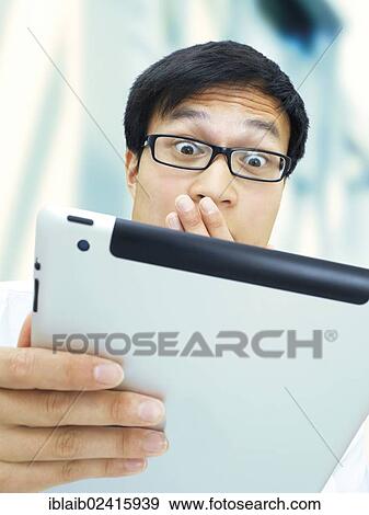 Young businessman, Asian, with glasses, iPad, amazed View Large Photo Image Stock Photo - Young businessman, Asian, with glasses, iPad, amazed. Fotosearch
