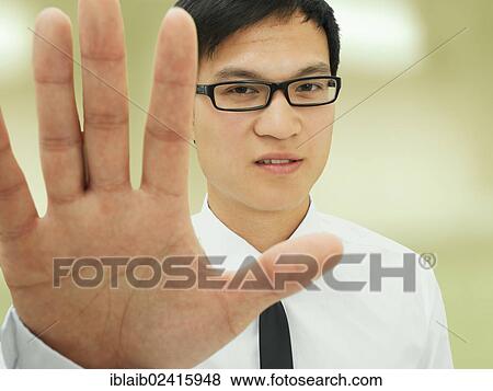 Young businessman, Asian, with glasses, holding hand forward, rejecting, serious View Large Photo Image Stock Photo - Young businessman, Asian, with glasses, holding hand forward, rejecting, serious. Fotosearch