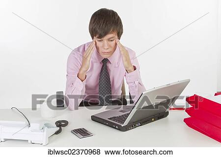 Young businessman looking stressed and having a headache View Large Photo Image Stock Photo - Young businessman looking stressed and having a headache. Fotosearch