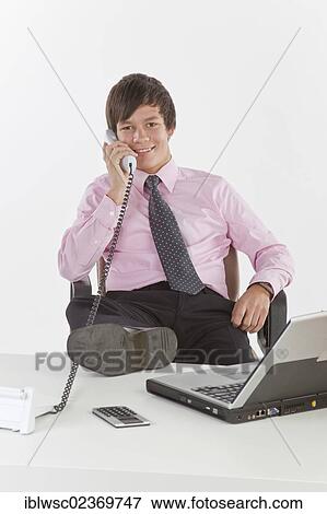 Young businessman talking on a phone in an office View Large Photo Image Stock Photo - Young businessman talking on a phone in an office. Fotosearch