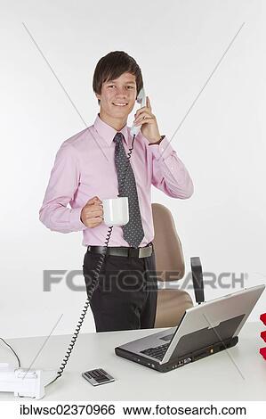 Stock Photograph - Young businessman talking on the phone in the office. Fotosearch
