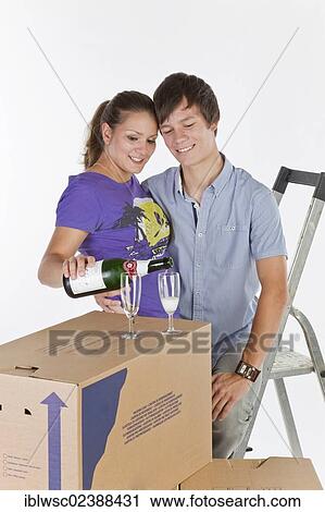 Stock Image - "Young couple, house moving, with a bottle of champagne". Fotosearch