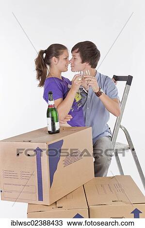 Stock Image - "Young couple, house moving, with a bottle of champagne". Fotosearch
