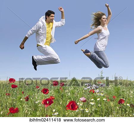 "Young couple jumping over a flower meadow in early summer, Bad Nenndorf, Lower Saxony, Germany, Europe" View Large Photo Image Stock Photo - "Young couple jumping over a flower meadow in early summer, Bad Nenndorf, Lower Saxony, Germany, Europe". Fotosearch