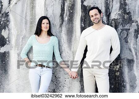 "Young couple standing hand in hand in front of a wall, Austria, Europe" View Large Photo Image Stock Image - "Young couple standing hand in hand in front of a wall, Austria, Europe". Fotosearch