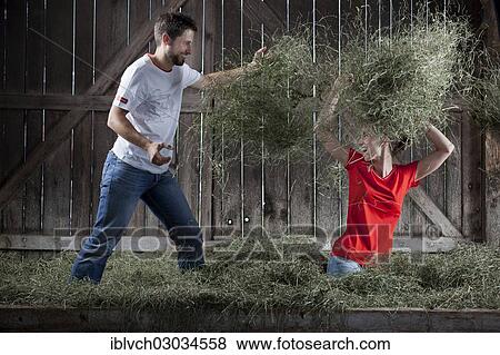 Stock Photo - "Young couple throwing hay at each other on a farm, Reith im Alpbachtal, Kufstein District, North Tirol, Tirol, Austria, Europe". Fotosearch