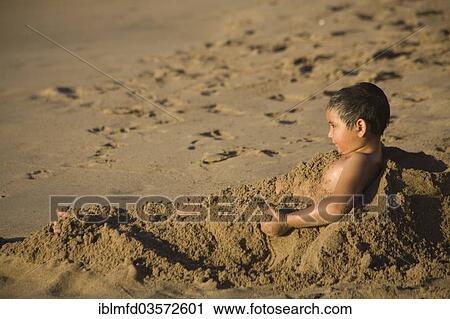 Stock Image - "Young covering himself with the sand on the beach, Puerto Vallarta, Jalisco, Mexico, North America". Fotosearch