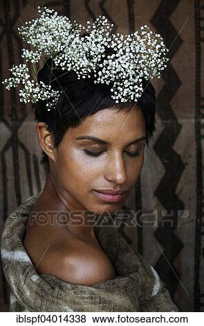 Stock Photo - Young dark-skinned woman with flowers on her head and closed eyes. Fotosearch