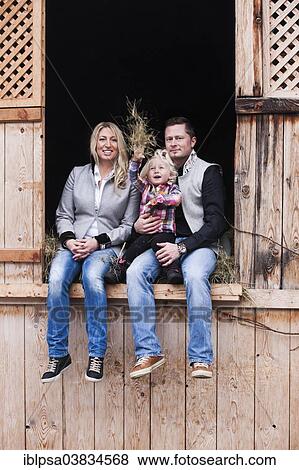 Stock Photo - "Young family sitting in the hay barn, North Tyrol, Austria, Europe". Fotosearch