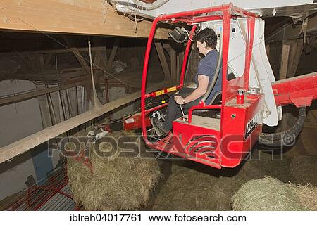Stock Image - "Young farmer using a hay crane, Sprenger family farm, Schwaz District, Tyrol, Austria Family". Fotosearch