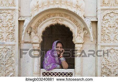 "Young friendly Indian woman wearing a headscarf looking out of a window opening of an ornate marble facade, Rat Temple of the goddess Karni Mata, Karni Mata Temple, Deshnok, Rajasthan, India, Asia" View Large Photo Image Stock Image - "Young friendly Indian woman wearing a headscarf looking out of a window opening of an ornate marble facade, Rat Temple of the goddess Karni Mata, Karni Mata Temple, Deshnok, Rajasthan, India, Asia". Fotosearch