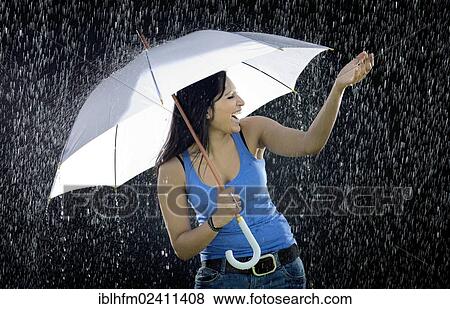 Young Indian woman holding a white umbrella while ecstatically enjoying the rain View Large Photo Image Stock Photo - Young Indian woman holding a white umbrella while ecstatically enjoying the rain. Fotosearch