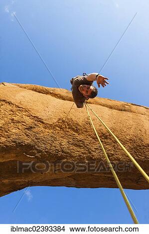 "Young man abseiling from a rock arch, hanging upside down, near the Spitzkoppe granite peaks, Damaraland, Namibia, Africa" View Large Photo Image Picture - "Young man abseiling from a rock arch, hanging upside down, near the Spitzkoppe granite peaks, Damaraland, Namibia, Africa". Fotosearch