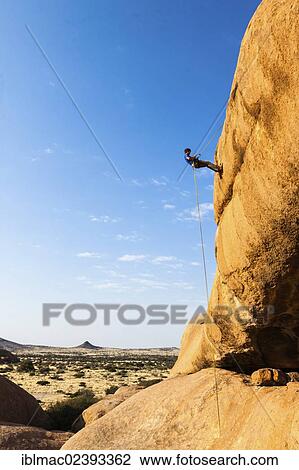 "Young man abseiling from a rock arch, near the Spitzkoppe granite peaks, Damaraland, Namibia, Africa" View Large Photo Image Stock Image - "Young man abseiling from a rock arch, near the Spitzkoppe granite peaks, Damaraland, Namibia, Africa". Fotosearch